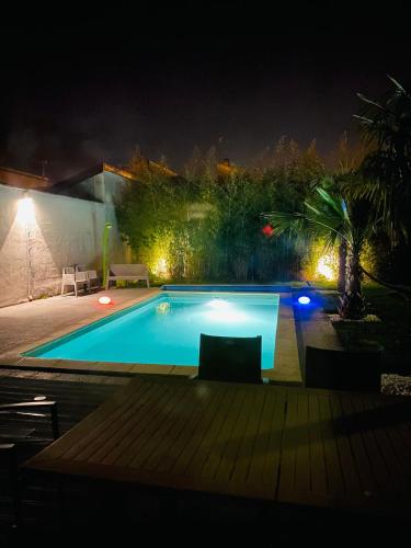 une piscine dans un jardin la nuit dans l'établissement La Villa Clauzets Piscine, à Reims