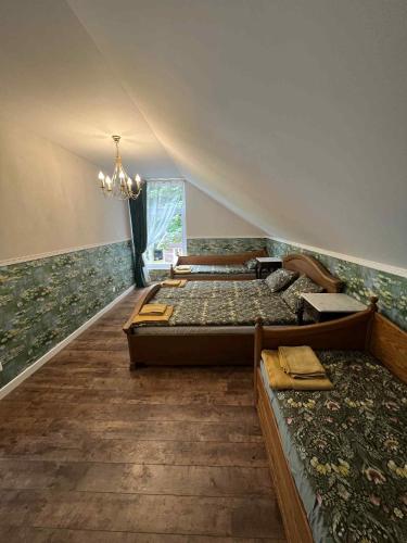 a bedroom with four beds and a chandelier at Sodyba "Septyni šeštadieniai" Plateliai in Paplatelė