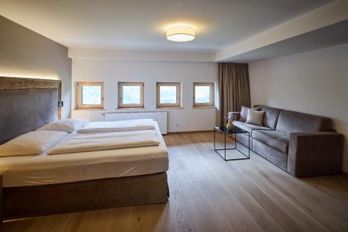a bedroom with a large bed and a couch at Designhotel Sonnhof by Vitus Winkler in Sankt Veit im Pongau