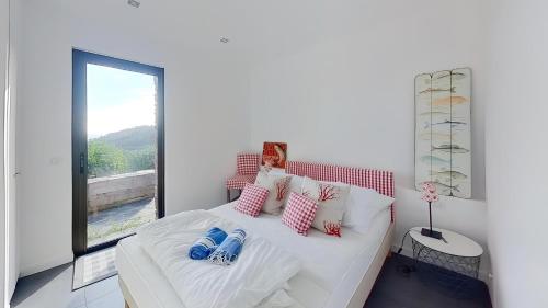 une chambre avec un lit blanc avec des oreillers et une fenêtre dans l'établissement CASA-Gaou-Benat splendid sea view villa, à Bormes-les-Mimosas