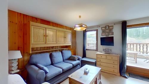 un salon avec un canapé bleu et une télévision dans l'établissement CASA-Amélie terrasse vue parking, à Vars