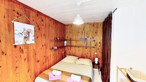 a bedroom with wooden walls and a bed with pink notes at Casa-Le Toussiard apart dans chalet St-Véran 4-6p in La Chalp-Sainte-Agathe