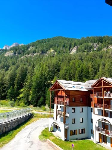 un immeuble d'appartements avec une montagne en arrière-plan dans l'établissement CASA-Bois de Pisan at the foot of the slopes, à Molines-en-Queyras