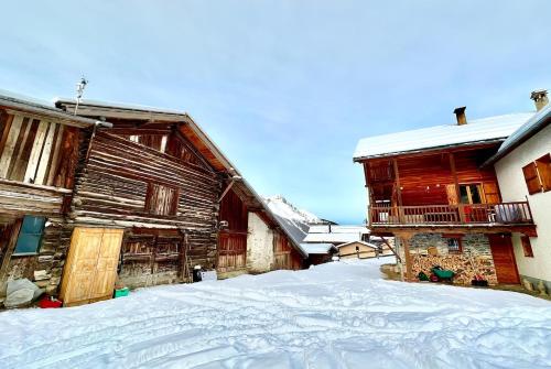 a snow covered yard in front of two wooden buildings at CASA-La Lobio foot of the slopes breathtaking views 4p in Saint-Véran
