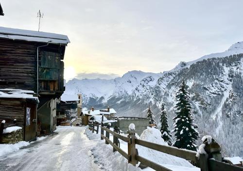 a snow covered street with a fence and mountains at CASA-La Lobio foot of the slopes breathtaking views 4p in Saint-Véran