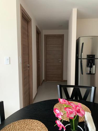 a table with pink flowers on top of it with a refrigerator at Apartamento en Cipreses San Ignacio, Tegucigalpa in Tegucigalpa
