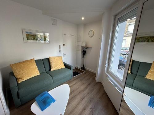 un salon avec un canapé vert et une fenêtre dans l'établissement Le Charmant Créneau - Basilique, à Reims