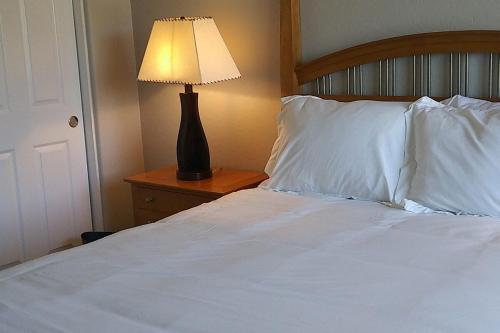 a bed with white sheets and a lamp on a night stand at VILLA Verde Surprise Stadium - Resort Living in Surprise