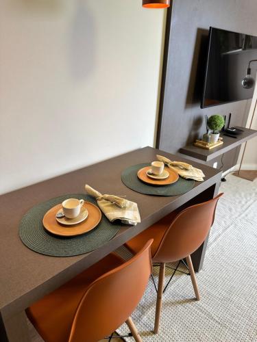 a table with two cups and plates on it at Summit Flat, ótima localização, limpeza diária, academia e piscina in São José dos Campos