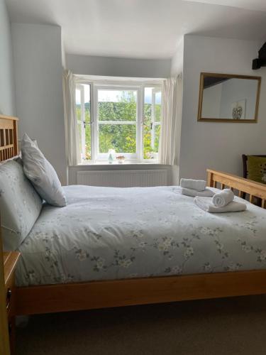 un dormitorio con una cama y una ventana en 200 year old Gardener's cottage, Mid Wales, en Llanidloes