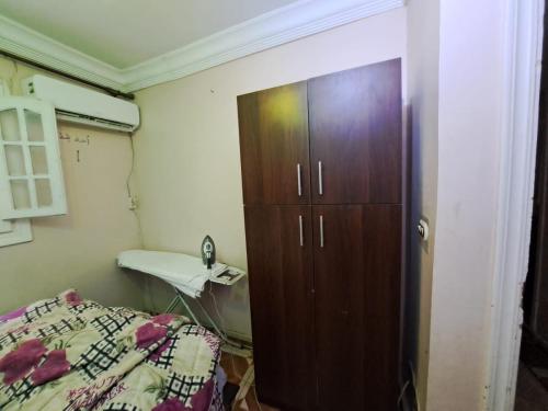 a bedroom with a wooden cabinet next to a bed at KENZY Apartment in Alexandria