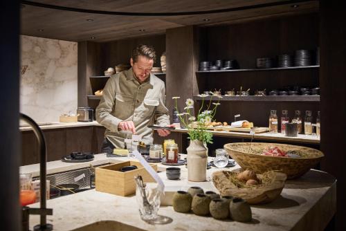 a man standing in a kitchen preparing food at Designhotel Sonnhof by Vitus Winkler in Sankt Veit im Pongau