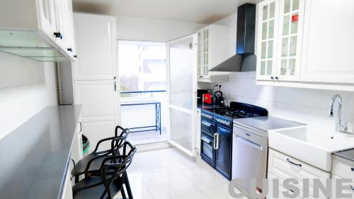 une cuisine avec des armoires blanches et des appareils bleus dans l'établissement 5 Chambres 3 Sdb Parking Gratuit - Idéal Groupe, à Créteil