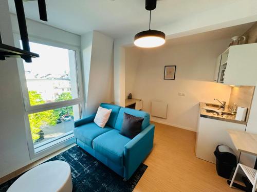 - un canapé bleu dans le salon doté d'une fenêtre dans l'établissement We Live In R - Duplex 502, à Reims
