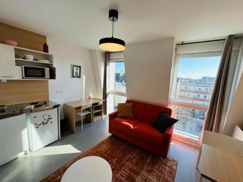 - un salon avec une chaise rouge devant une fenêtre dans l'établissement We Live In R - Duplex 501, à Reims