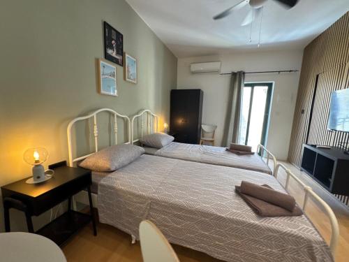 a bedroom with two beds and a table and a television at Bentley Floriana Suites in Il-Furjana