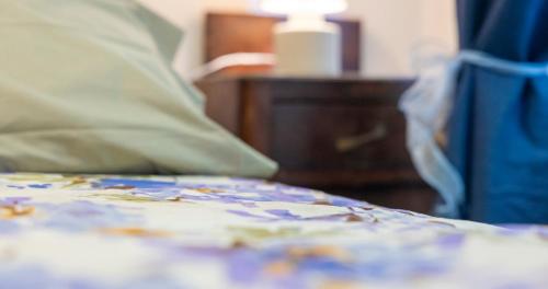 a bed with a comforter and a night stand with a lamp at A magical place to regenerate in Bagnolo
