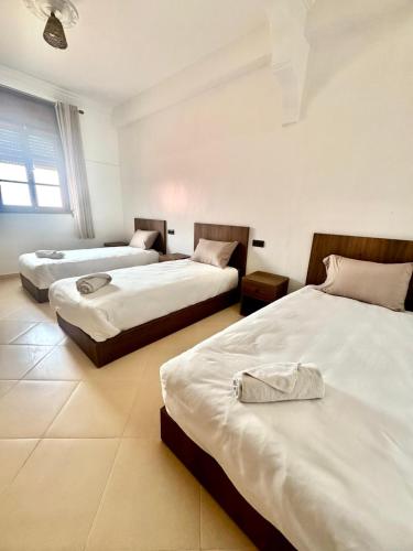 a room with three beds in a room at SurfsHub Hostel Tamraght in Tamraght Ouzdar