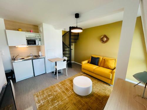 un salon avec un canapé jaune et une cuisine dans l'établissement We Live In R - Duplex 503, à Reims