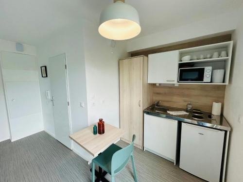 a small kitchen with a table and a microwave at We Live In R - Suite 201 in Reims
