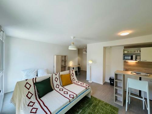 a room with a bed and a desk and a kitchen at We Live In R - Suite 203 in Reims