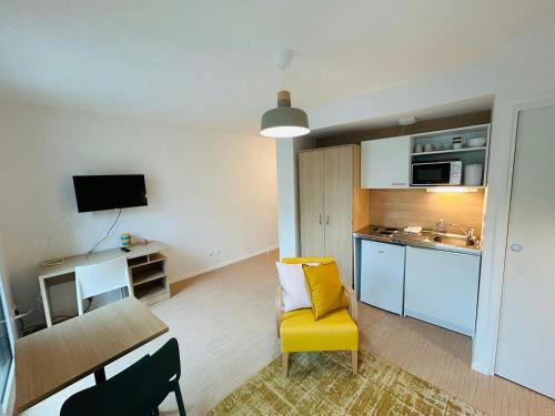un salon avec une chaise jaune et une cuisine dans l'établissement We Live In R - Suite 302, à Reims