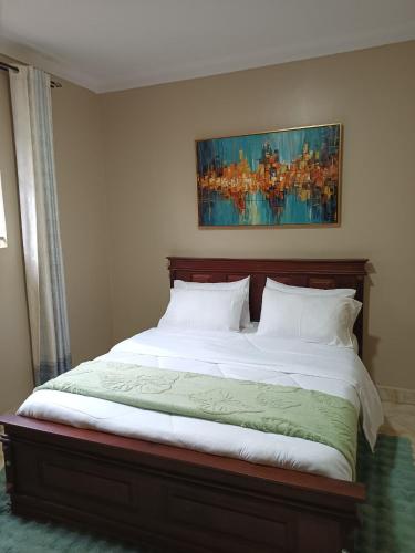 a bed in a bedroom with a painting on the wall at Lerato's Apartments in Kampala