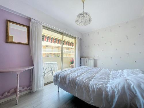 une chambre avec un lit, une fenêtre et un lustre dans l'établissement Estivalière - 6 couchages - 3 chambre - Parking, au Golfe-Juan
