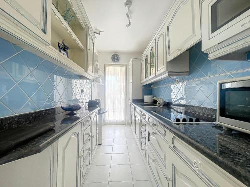 une cuisine avec des placards blancs et du carrelage bleu dans l'établissement Estivalière - 6 couchages - 3 chambre - Parking, au Golfe-Juan