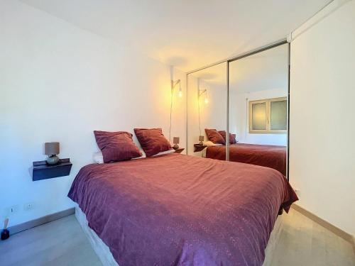 une chambre avec deux lits et un grand miroir dans l'établissement Residence Piscine -4 couchages -1 chambre- parking, au Golfe-Juan