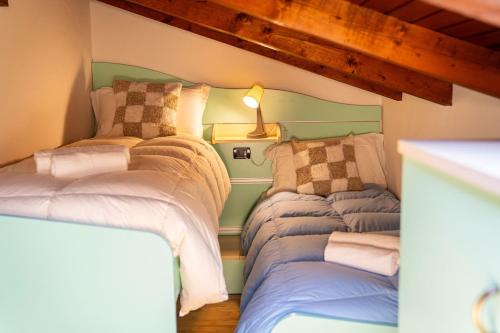 a room with two beds and a lamp on the wall at Mansarda di Gallio - Mountain Escape in Gallio
