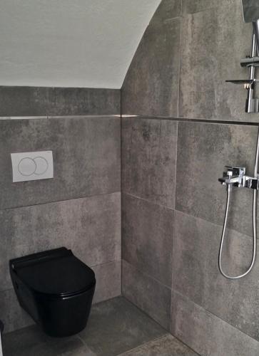 a bathroom with a black toilet and a shower at Adventure Camping Kosovo in Prizren