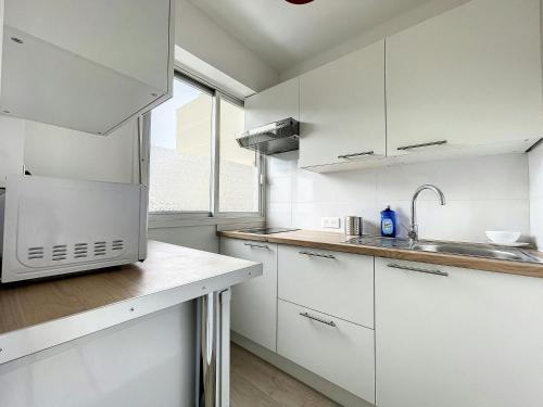 une cuisine blanche avec des armoires blanches et un évier dans l'établissement Studio Centreville Golfe Juan-2 couchages-Terrasse, au Golfe-Juan
