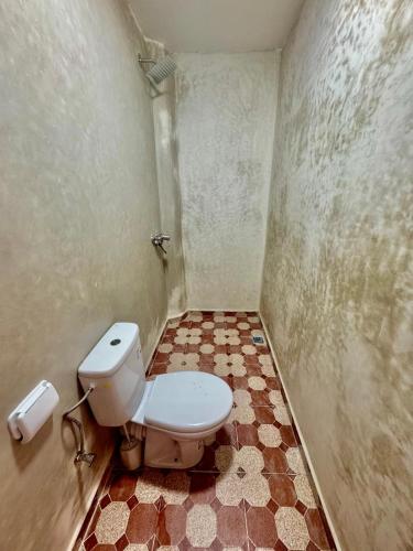 a bathroom with a toilet and a tiled floor at SurfsHub Hostel Tamraght in Tamraght Ouzdar