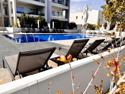 una fila di sedie sedute accanto a una piscina di Too Coool Apartment Mythical Seas 5 a Paralimni