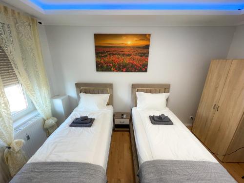 two beds in a room with a painting on the wall at Atlas-Apartment in Magdeburg