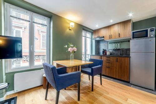 une cuisine avec une table en bois et des chaises bleues dans l'établissement Studio Matcha - 10min to Paris, à Fontenay-sous-Bois