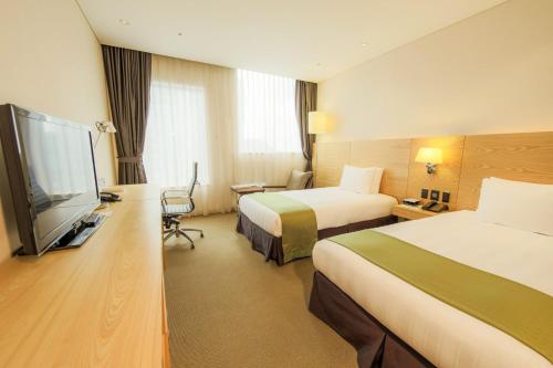 a hotel room with two beds and a flat screen tv at Holiday Inn Gwangju by IHG in Gwangju