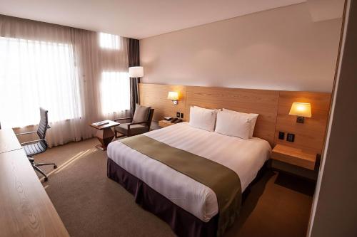 a hotel room with a large bed and a chair at Holiday Inn Gwangju by IHG in Gwangju
