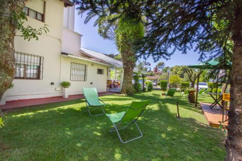 einen Garten mit Stühlen und ein Haus in der Unterkunft hosteria Dalmacia in Pinamar