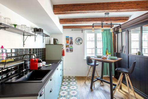 une cuisine avec des comptoirs noirs et une petite table dans l'établissement Hyper centre Colmar The Factory Room, à Colmar