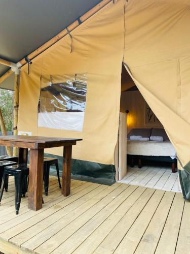 a tent with a wooden table and a bed at Parque Laguna de Zapallar in Maitencillo