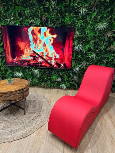 a red chair in a living room with a fireplace at F & C Love Spa, Sauna and Tantra in Chartrettes