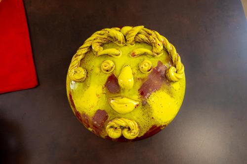 a yellow sculpture of a face on a table at La dimora dei ricci in Santo Stefano di Camastra