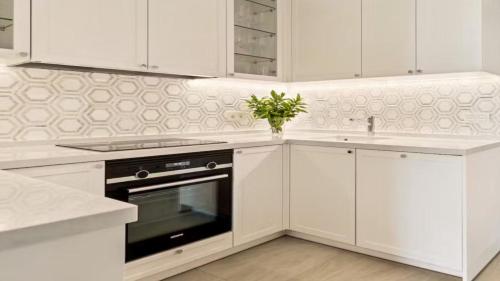a white kitchen with a stove and a sink at Private Villa Houlakia Mikonos in Agios Stefanos