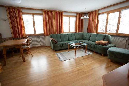 a living room with a green couch and a table at Appartements Willi in Schoppernau