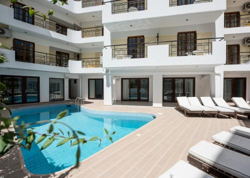 un edificio de apartamentos con piscina y sillas en Artemis Hotel Apartments en Hersonissos