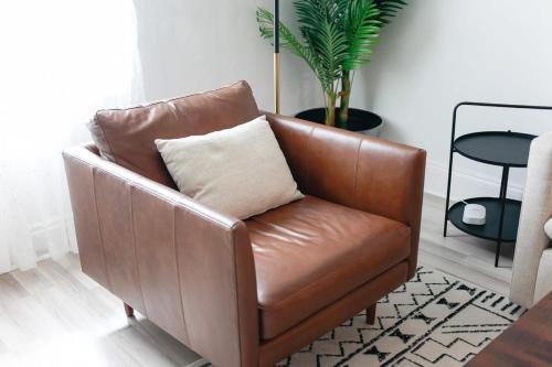 a brown leather chair with a pillow in a living room at Sojourn on the Bay 2 BR Private Beach Access in Norfolk
