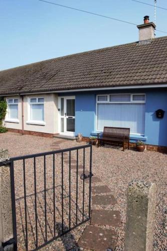 a blue house with a bench in front of it at Cosy Coastal Cottage in Portballintrae in Portballintrae