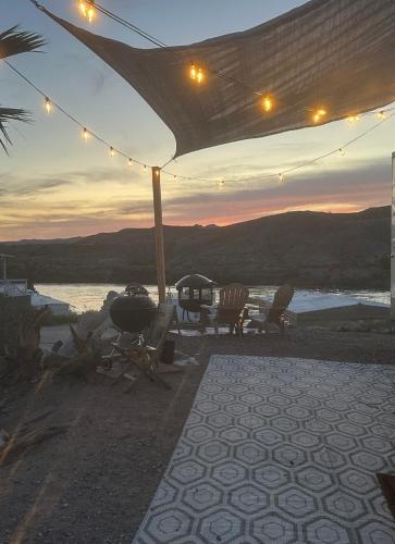 a patio with chairs and a grill and a sunset at Fisher Paradise Oasis on the River in Bullhead City
